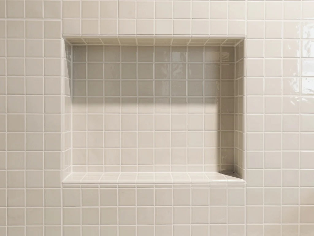 Faïence murale claire et niche de rangement au-dessus d'une douche rénovée